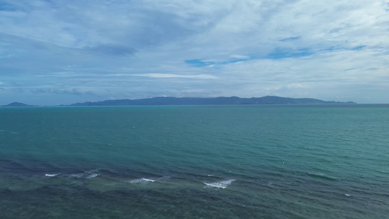 Aerial drone footage flying from Koh Phangan beach towards Koh Samui, showcasing turquoise waters, tropical islands, and scenic coastline