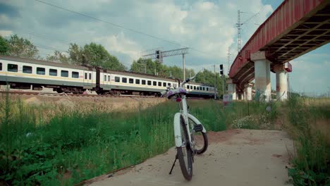 a slow running train in the railway and a white bike