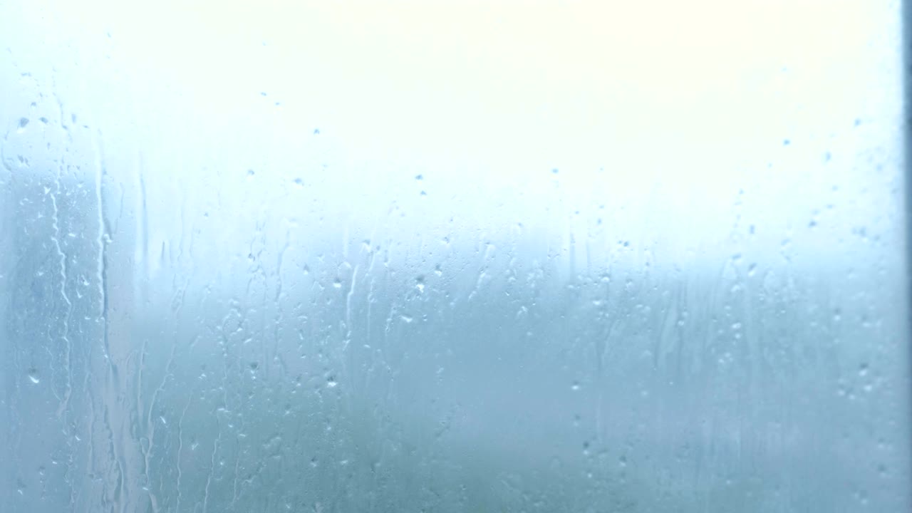 las gotas de lluvia fluyen por el vidrio en primer plano.