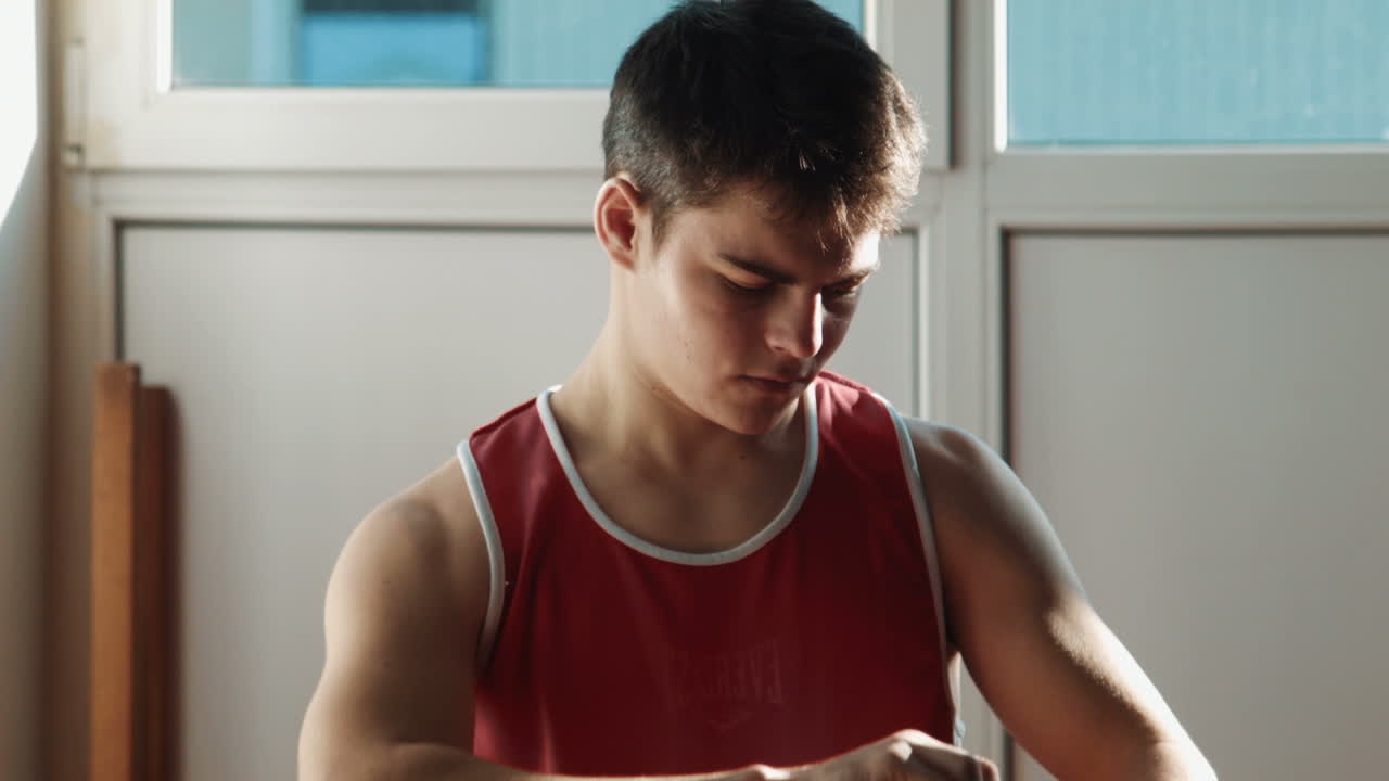 The Young Boxer Pulls Red Bandage on Hands