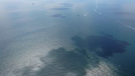 aerial view of tranquil ocean waters with distant ships and reflection patterns on the surface, capturing the serenity of maritime life