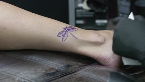 The-copy-paper-with-the-drawing-of-the-tattoo-is-removed,-leaving-an-imprint-on-the-client's-skin