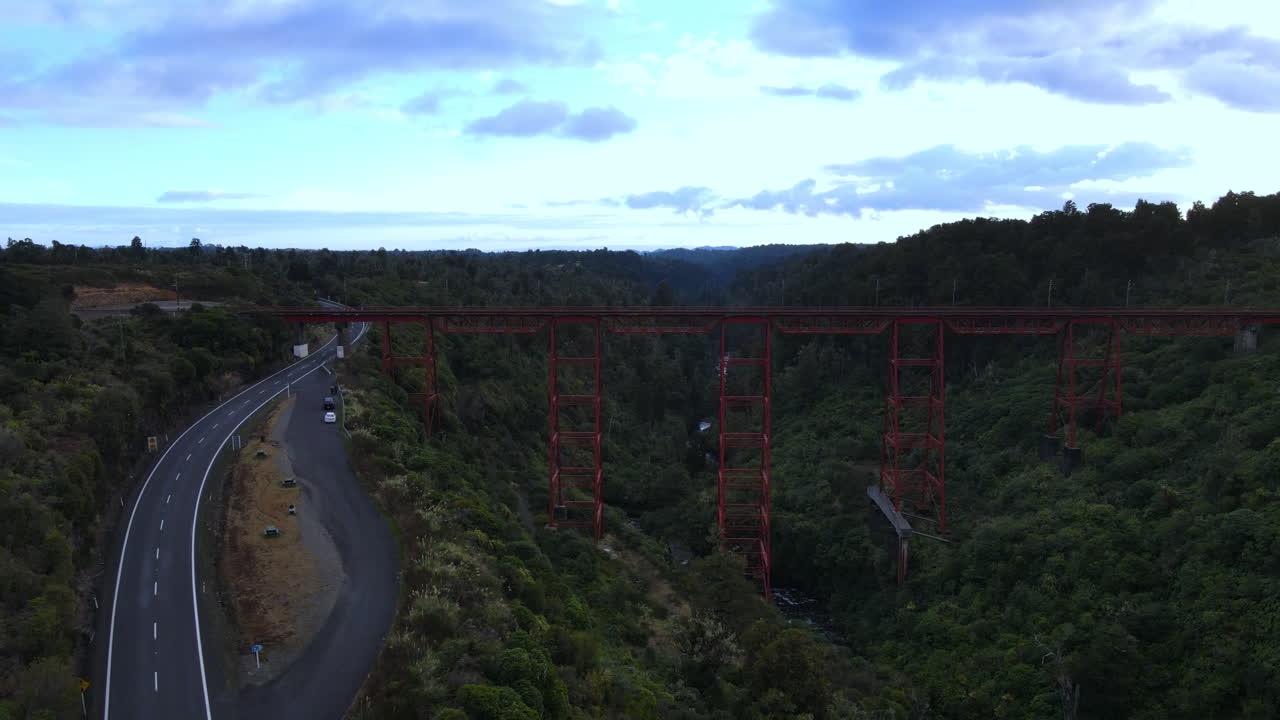 tiro de retroceso de drones del puente ferroviario rojo sobre george con árboles y río y carretera