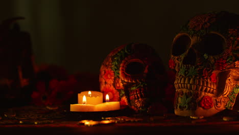 close up on still life of decorated skulls with candles and flowers celebrating mexican holiday of dia de muertos or day of the dead