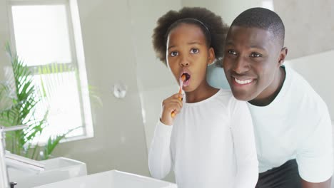 Video-of-african-american-father-and-daughter-brushing-teeth