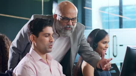 indian man employee busy working on computer while interacting to senior boss.