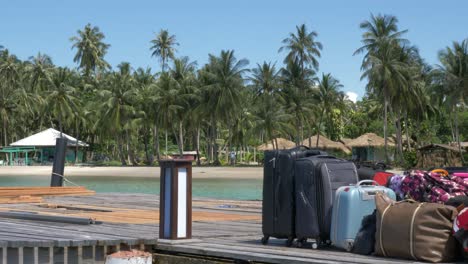 group of unattended luggage and suitcases on a wooden pier near an island shore