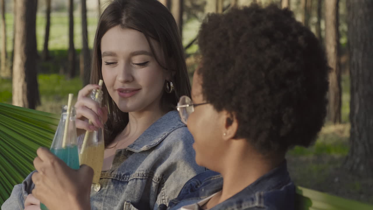 dos bestias brindando alegremente con sus refrescos sentados en sus hamacas en el bosque