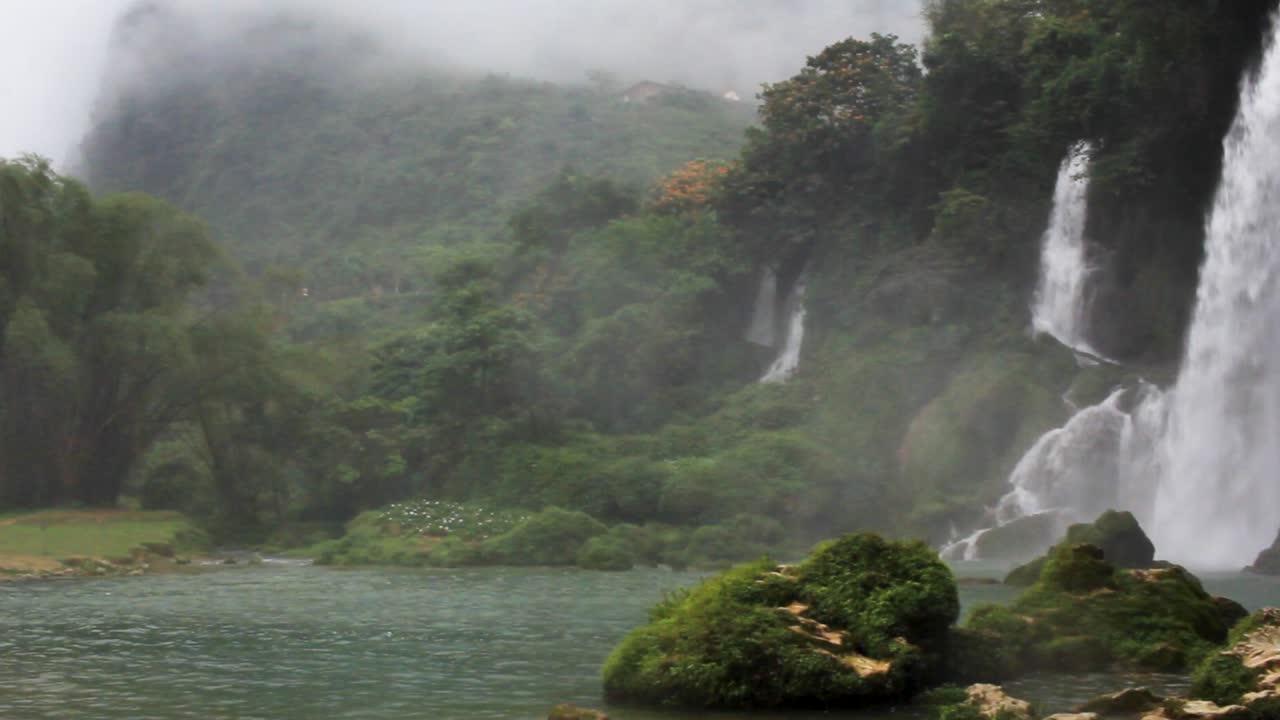 Pan left of a waterfall in Ban Gioc Vietnam with myst