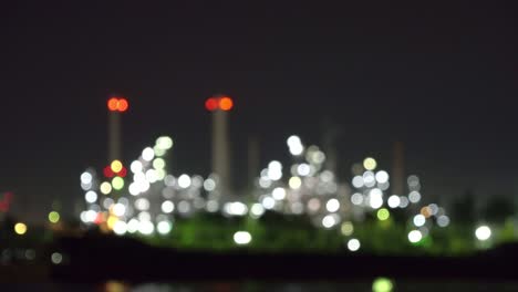 bokeh blurry background of petrochemical oil refinery and sea in industrial engineering concept, bangkok, thailand. oil and gas tanks pipelines in industry. modern metal factory with lights at night.