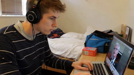young man wearing headphones watching a video on laptop