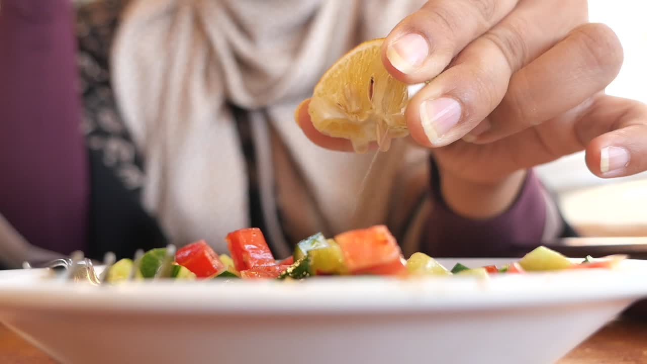 A woman squeezing lemon on a salad