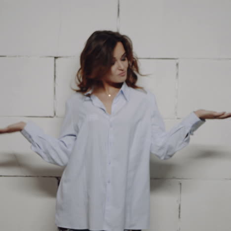 woman posing in a blue striped shirt in front of a brick wall
