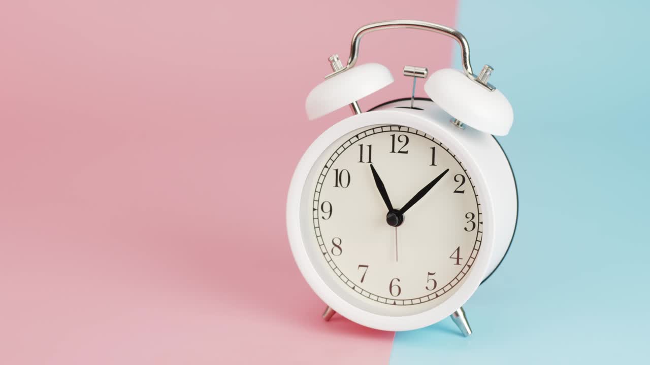 White alarm clock tell the time 12 o'clock.