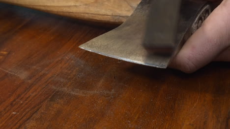 Tool-closeup:-Man-sharpens-old-axe-edge-with-whetstone-on-countertop