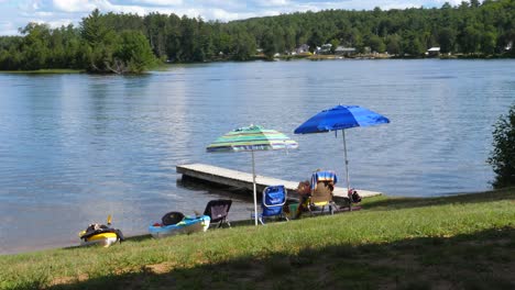 chairs, umbrellas, kayaks near the dock and water - relaxing at cottage lake house outdoors in summer