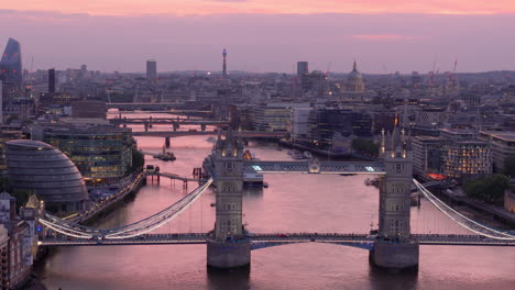 Illuminated-City-of-London-at-twilight-with-Tower-Bridge-over-Thames,-aerial