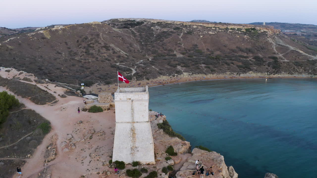 torre de piedra con la bandera de los caballeros de la orden de malta sobre una bahía,antena