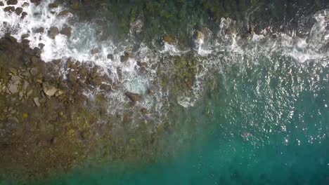 vista a volo d'uccello di un frangiflutti roccioso e onde che colpiscono contro di esso