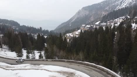 Furgoneta-Familiar-Plateada-Con-Caja-De-Techo-Conduciendo-Por-Carreteras-Nevadas-Y-Retorcidas-En-Montañas-Invernales