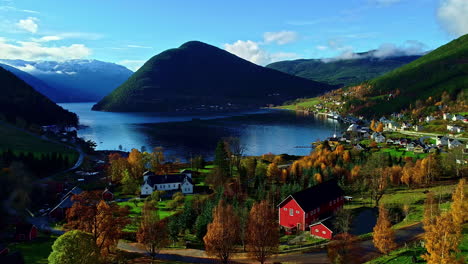 Un-Suave-Plano-Inverso-De-Un-Paisaje-Rústico-De-Un-Lago-Rodeado-Por-Un-Asentamiento-Montañoso