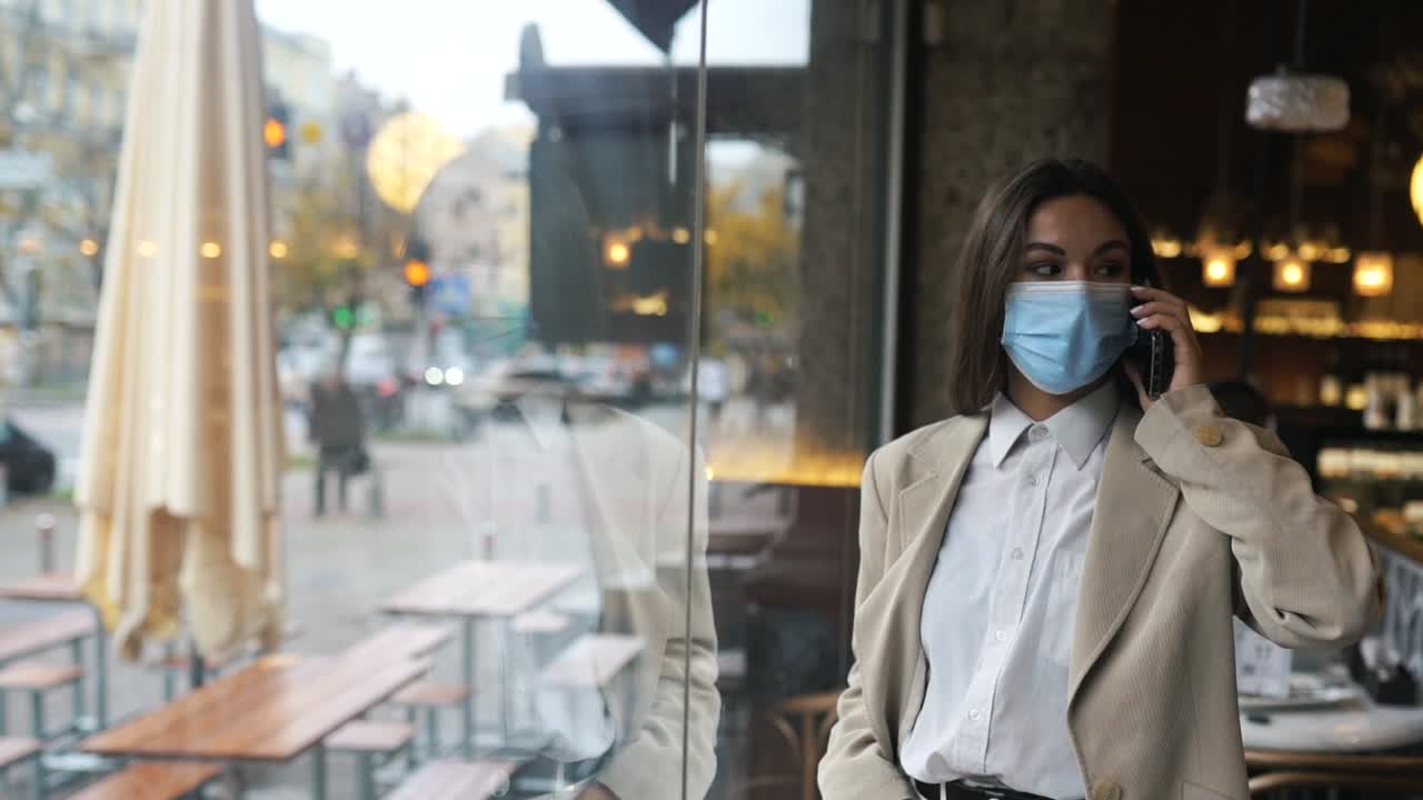 mujer hablando por teléfono en un café, usando una máscara