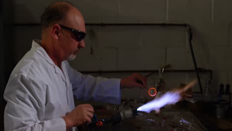 Side-view-of-mature-male-worker-blowing-glass-in-glass-factory-4k