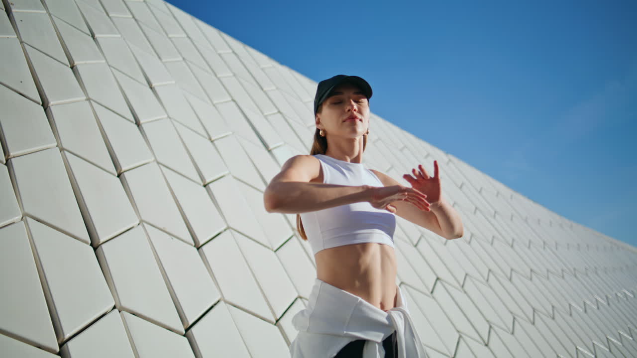 Slim lady warming up near contemporary street wall closeup. Energetic woman