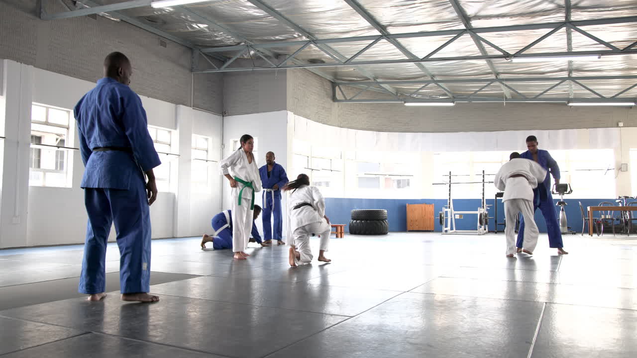 Practicing judo, students sparring in dojo with instructor supervising