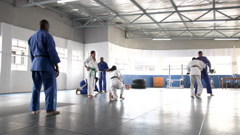 practicing judo, students sparring in dojo with instructor supervising