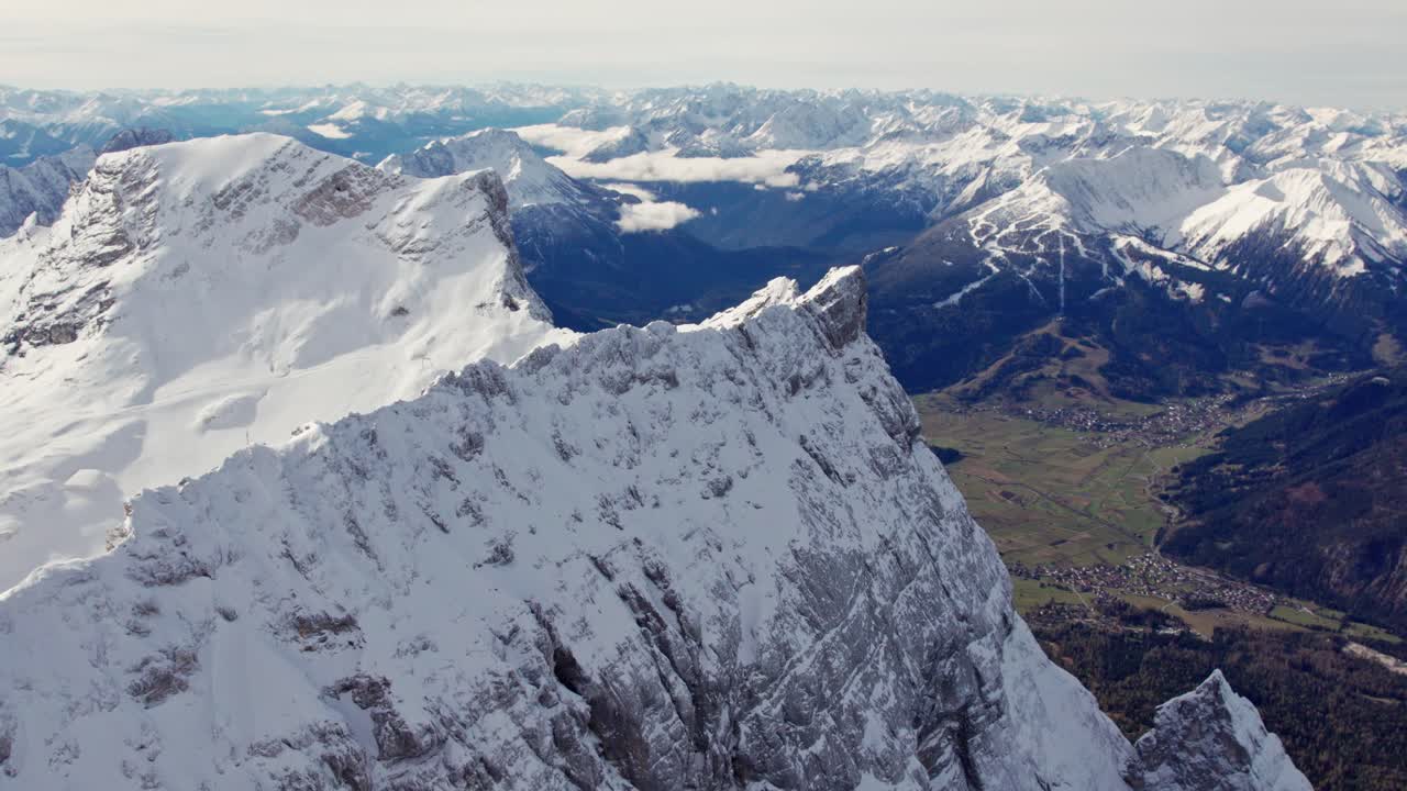 antena de una cumbre nevada en los alpes con el valle verde debajo