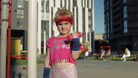 caucasian girl in sportswear making exercises with dumbbells. workout for kids. athletic child