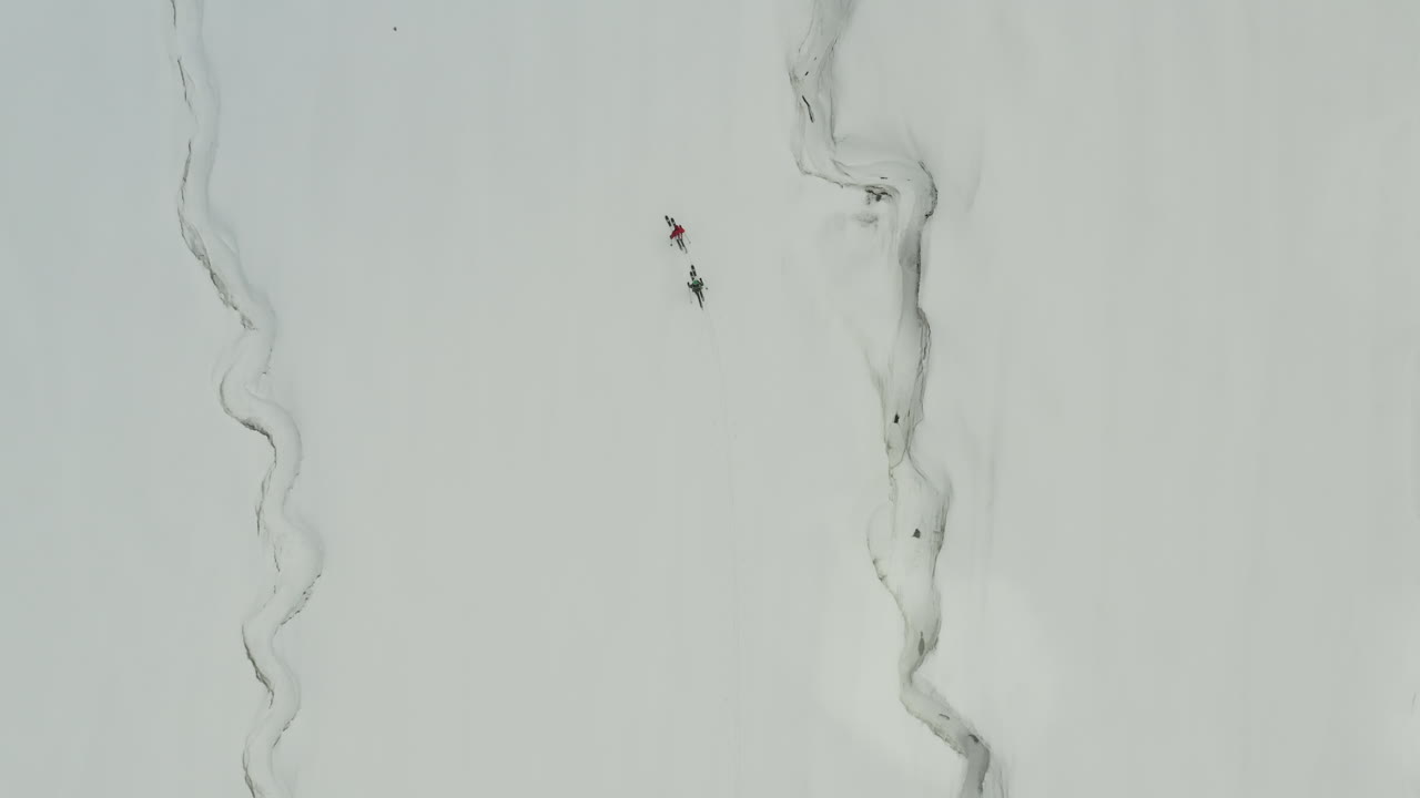 Two people skiing along a snow-covered mountain in kyrgyzstan, aerial view
