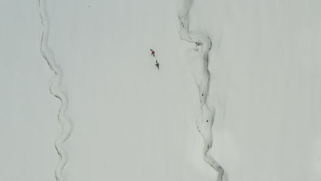two people skiing along a snow-covered mountain in kyrgyzstan, aerial view