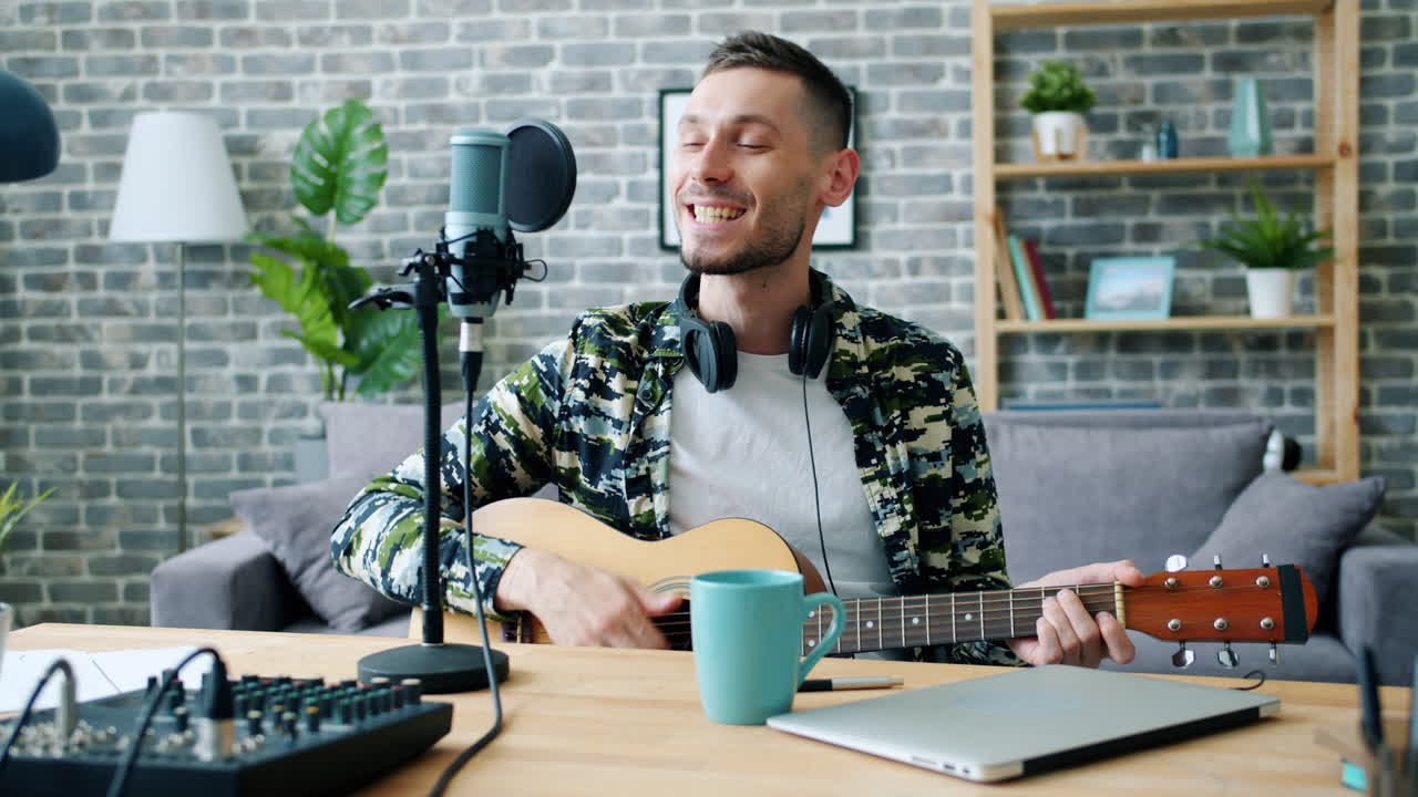 Man Singing and Playing Acoustic Guitar in Home Recording Studio