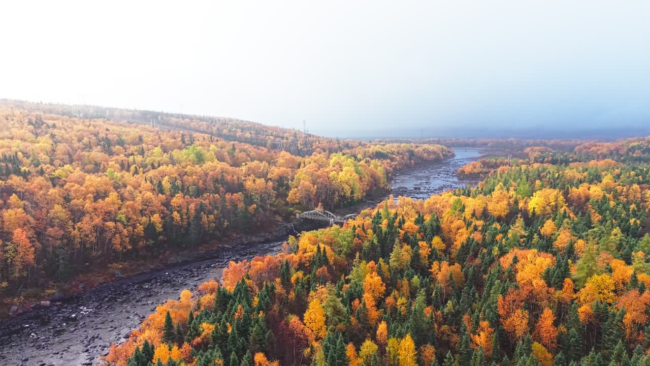 Drone footage shows serene lake reflecting autumn hills with orange and green foliage