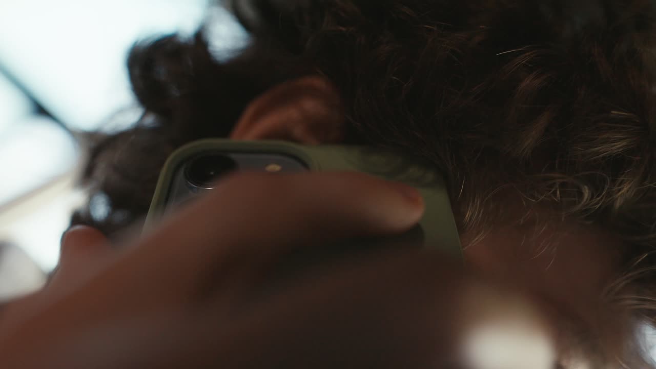 cerca un tipo con el cabello rizado saca un teléfono inteligente verde del bolsillo de sus pantalones y comienza la comunicación de negocios en la oficina