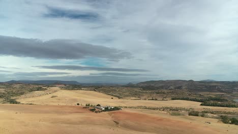 drone footage of vast, dry agricultural fields and rolling hills under a cloudy sky. rural landscape showing effects of drought in andalusia, spain