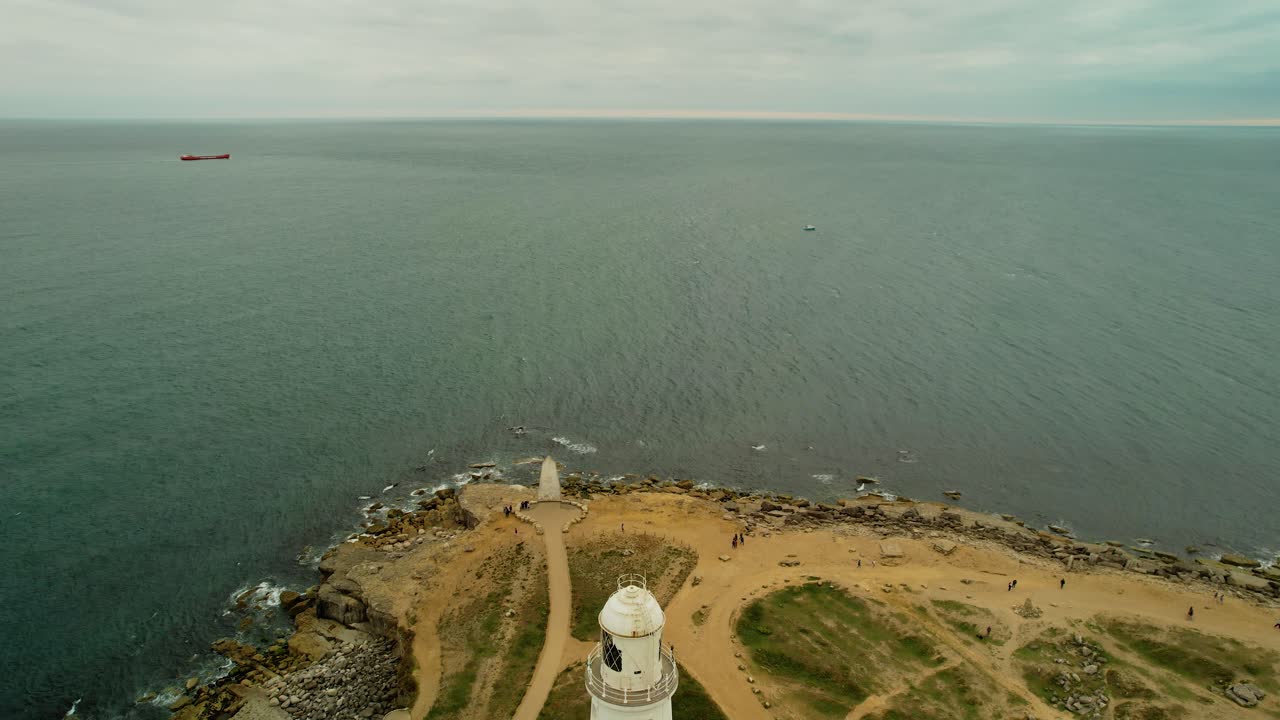 barco navegando en mar abierto con vista de cerca del faro rojo y blanco, vista aérea descendente