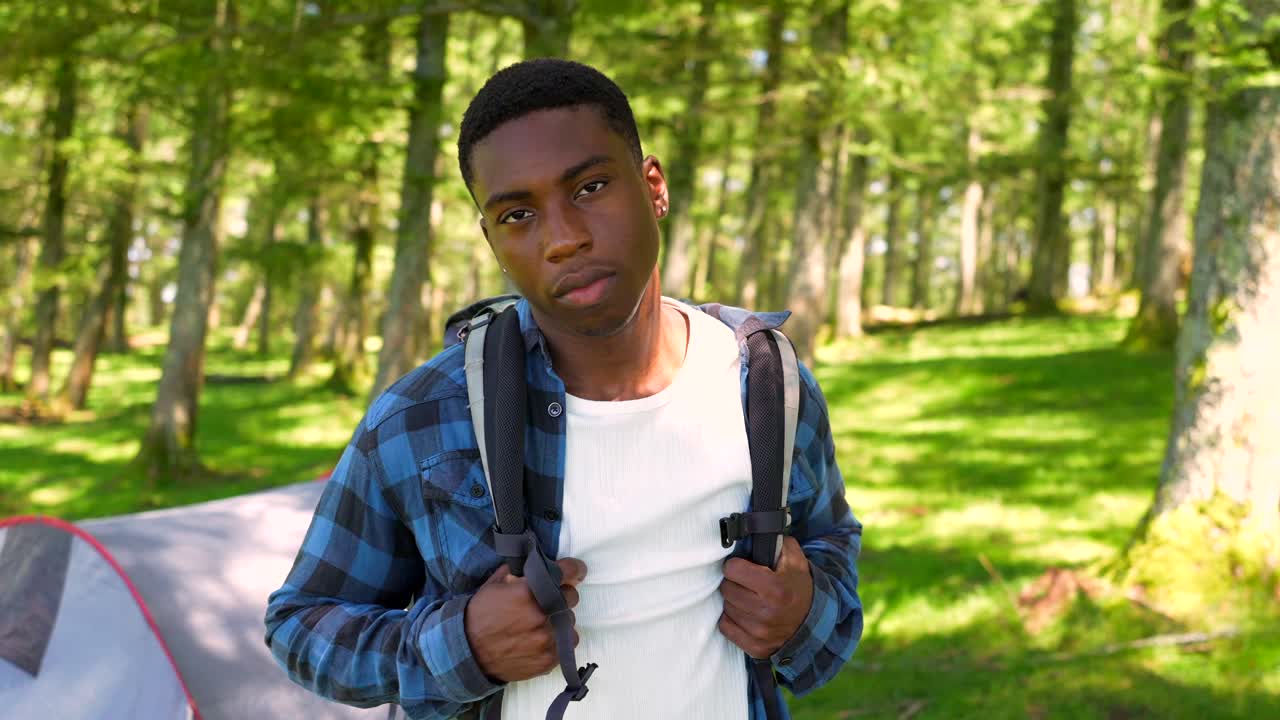 Young man camping in the forest with a backpack and tent