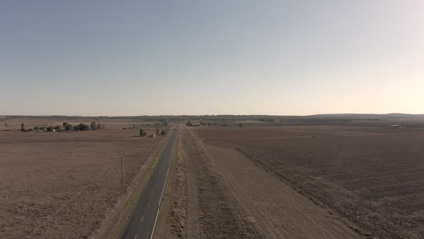 toma amplia aérea que se eleva verticalmente para revelar más del paisaje afectado por la sequía, mientras un vehículo blanco pasa a toda velocidad por la carretera