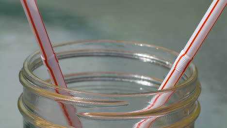 hand taking a bunch of single use plastic straws out of a glass jar