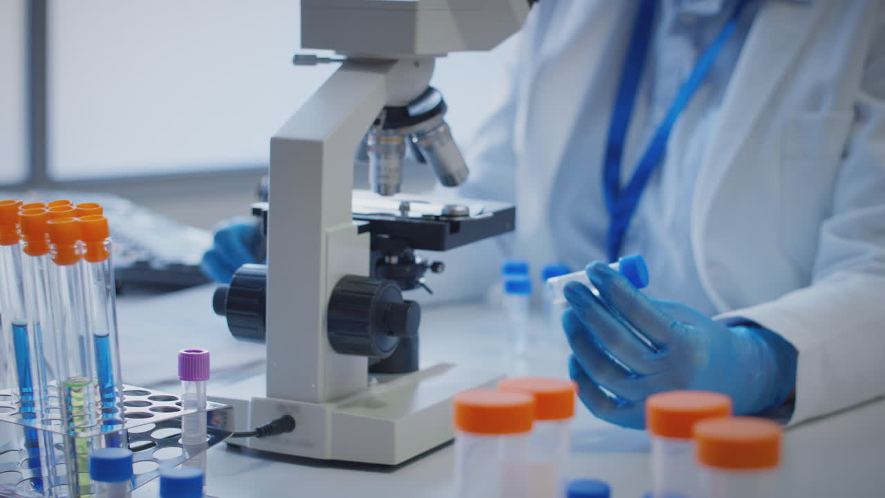 primer plano de un trabajador de laboratorio que lleva a cabo investigaciones utilizando un microscopio con un tubo de ensayo etiquetado como gamma
