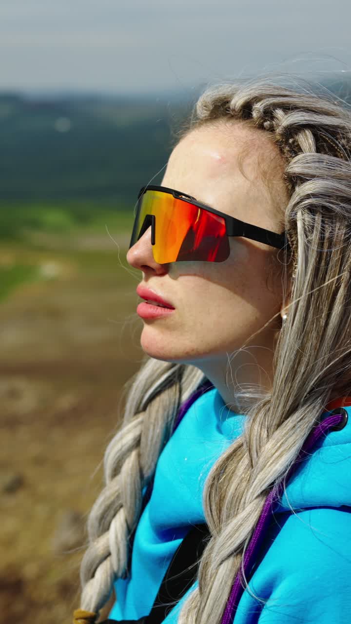Young Woman with Dreadlocks and Sunglasses Looking Out at Nature