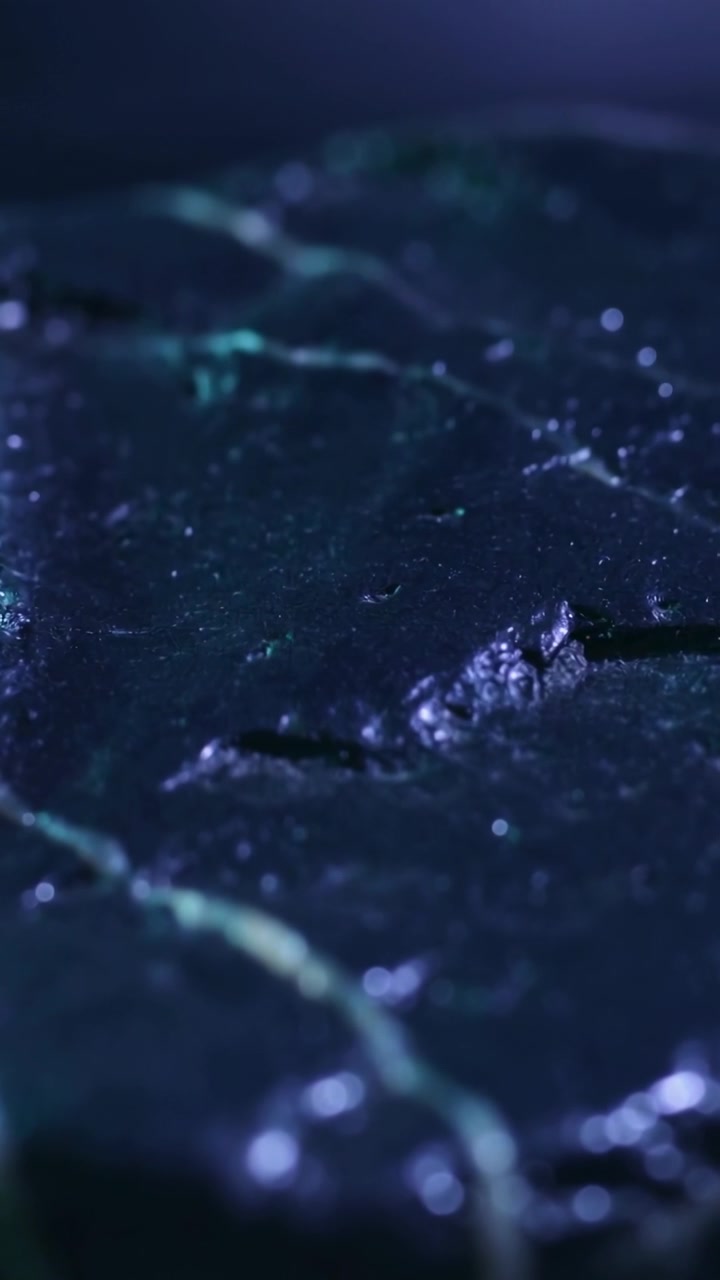 Vertical video: Camera shifting focus, lighting revealing sharper ridge on studio slab with veins