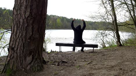 a man sitting on a bench by the lake is stretching