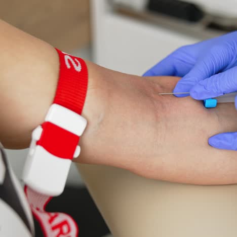 nurse in sterile gloves taking vein blood. doctor pricks needle into patient's arm in hospital laboratory. blood sampling for corona virus antibodies. close-up