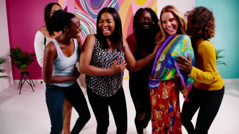 joyful group of women laughing and interacting in a colorful studio