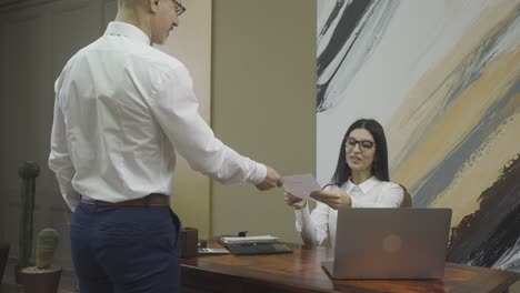 male employee giving document to his boss and then, they shaking hands at the office