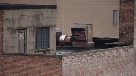 On-the-top-of-rusted,-urban,-buildings-with-smokestacks,-HVAC-vents,-fans,-and-brick-backgrounds